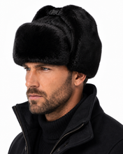 Load image into Gallery viewer, A man wearing a black fur ushanka hat and a black jacket, shown in a close-up profile against a white background.
