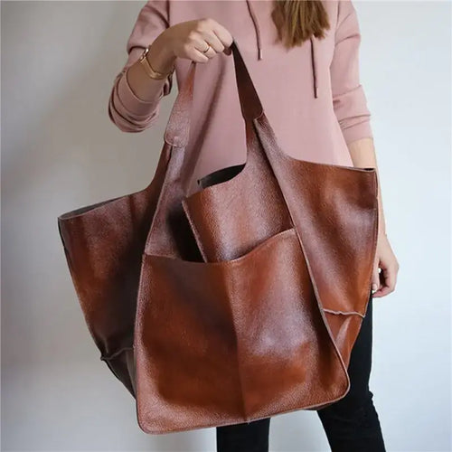 Vegan leather women's shoulder bag with large capacity and luxurious design, soft brown material, held by a person for size reference.