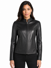 Cargar imagen en el visor de la galería, A woman modeling a black real-leather moto jacket with a stand collar and front zipper, paired with black pants, against a plain white background.
