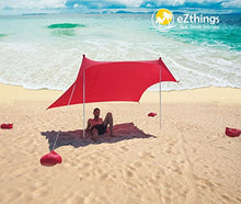 Load image into Gallery viewer, Royal Blue eZthings UV Light Sun Shade Protection Beach Shelter on sandy beach with sandbag anchors, providing 98% UV protection.
