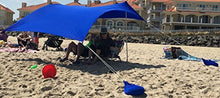 Load image into Gallery viewer, Royal blue UV sun shade beach shelter with sandbag anchors, providing sun protection and air circulation for beachgoers.
