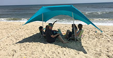 Load image into Gallery viewer, Group relaxing under eZthings UV light sun shade beach shelter with sandbag anchors, providing sun protection on the sandy beach.

