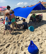 Load image into Gallery viewer, Royal Blue UV Light Sun Shade Protection Beach Shelter with Sandbag Anchors providing sunburn protection on a sunny beach day.
